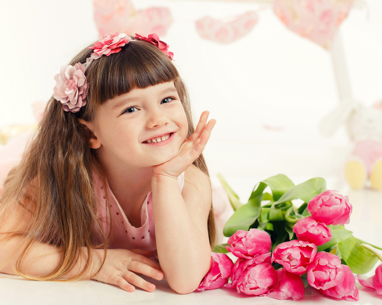 Красивая длинноволосая улыбающаяся девочка с букетом розовых тюльпанов