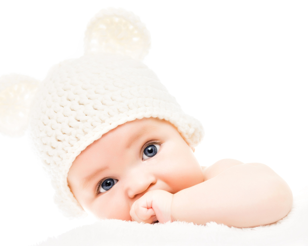 Голубоглазый младенец с белой шапке с ушками на белом фоне