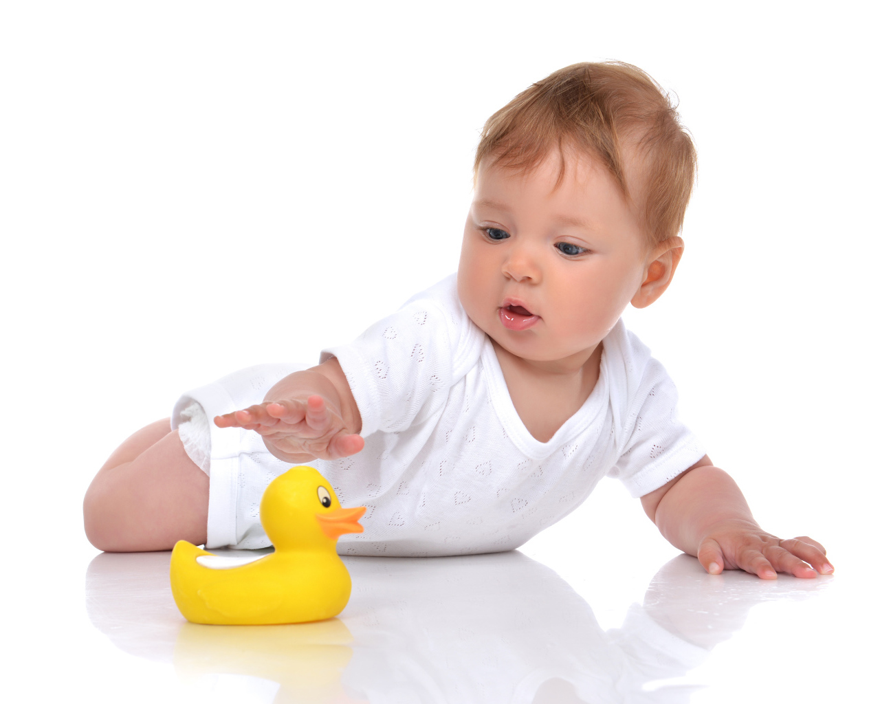Грудной ребенок с желтой резиновой уточкой на белом фоне