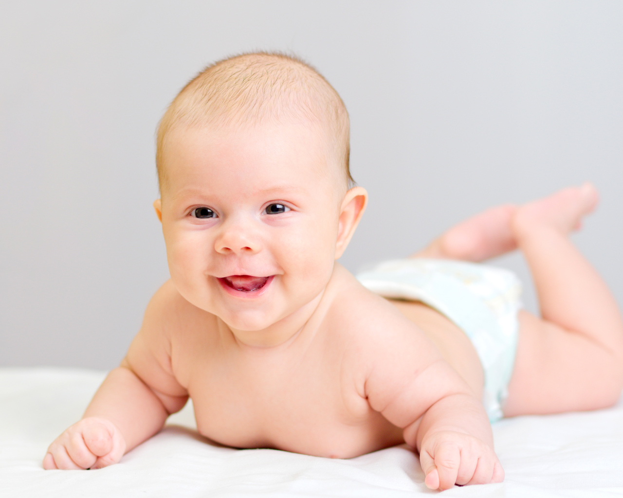 Милый улыбающийся ребенок на сером фоне