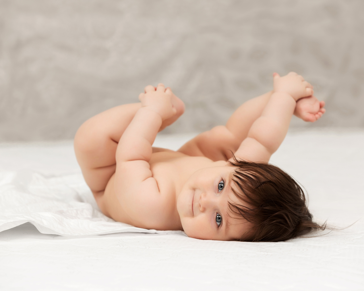 Забавный младенец держится руками за ноги 