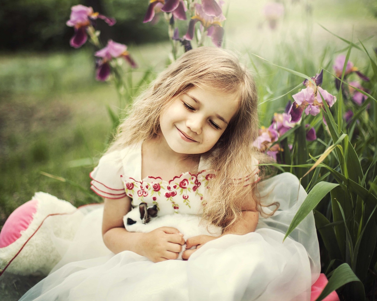 Маленькая девочка блондинка держит в руках кролика