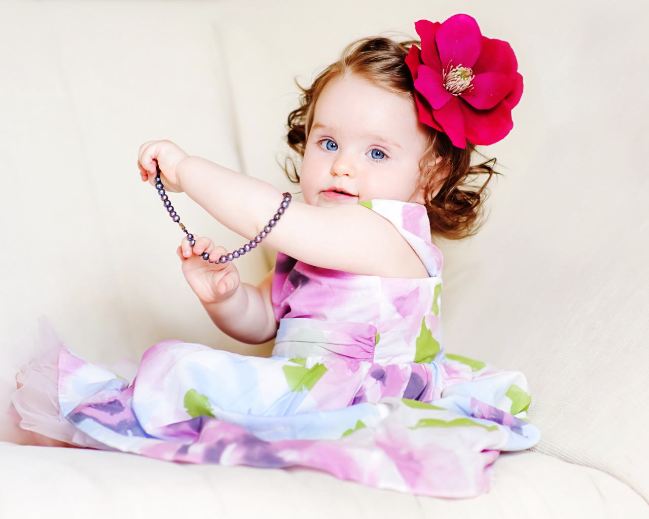 Маленькая голубоглазая девочка с красным цветком в волосах