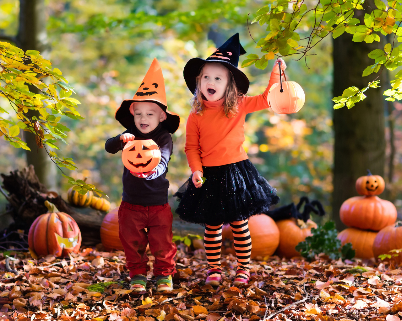 Маленькие мальчик и девочка в костюмах с тыквами на Хэллоуин