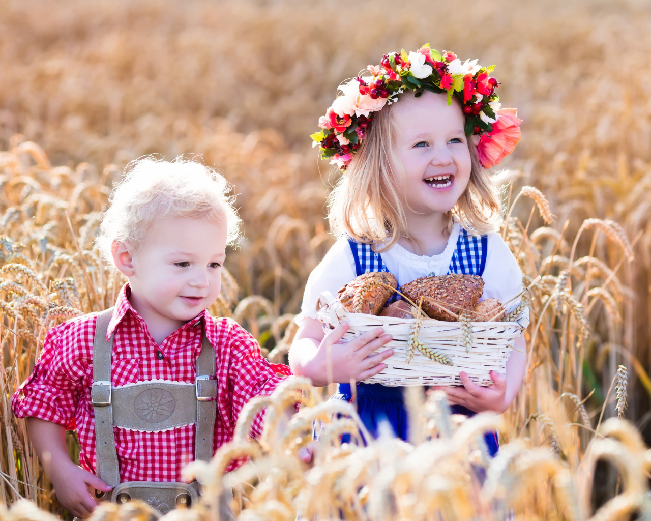 Маленькие мальчик и девочка на поле пшеницы с корзиной свежей выпечки