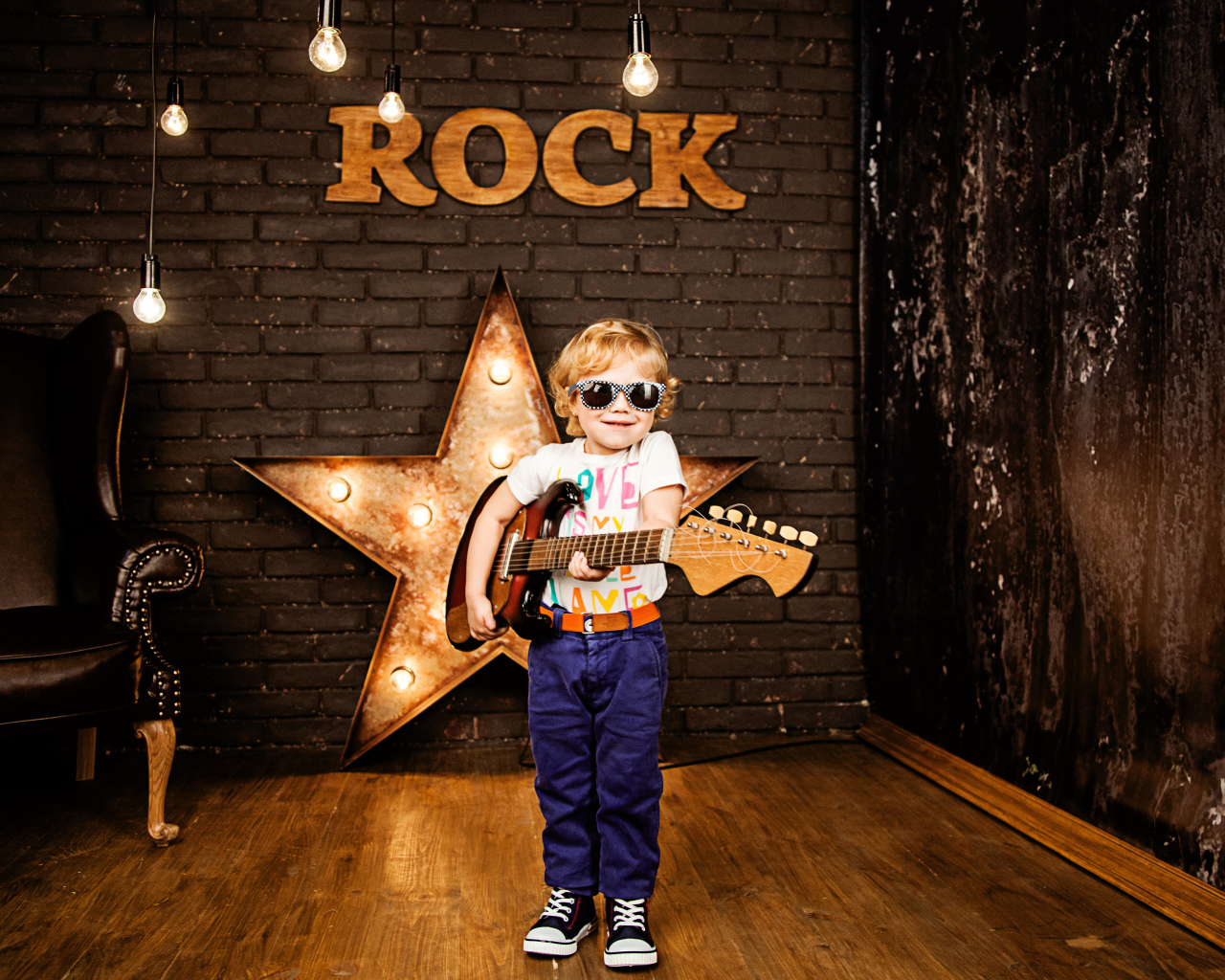 Маленький мальчик в модных очках с гитарой