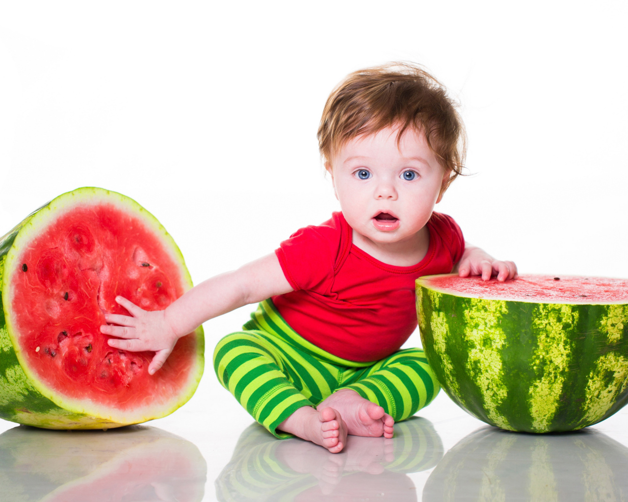Маленький мальчик с половинами арбуза на белом фоне