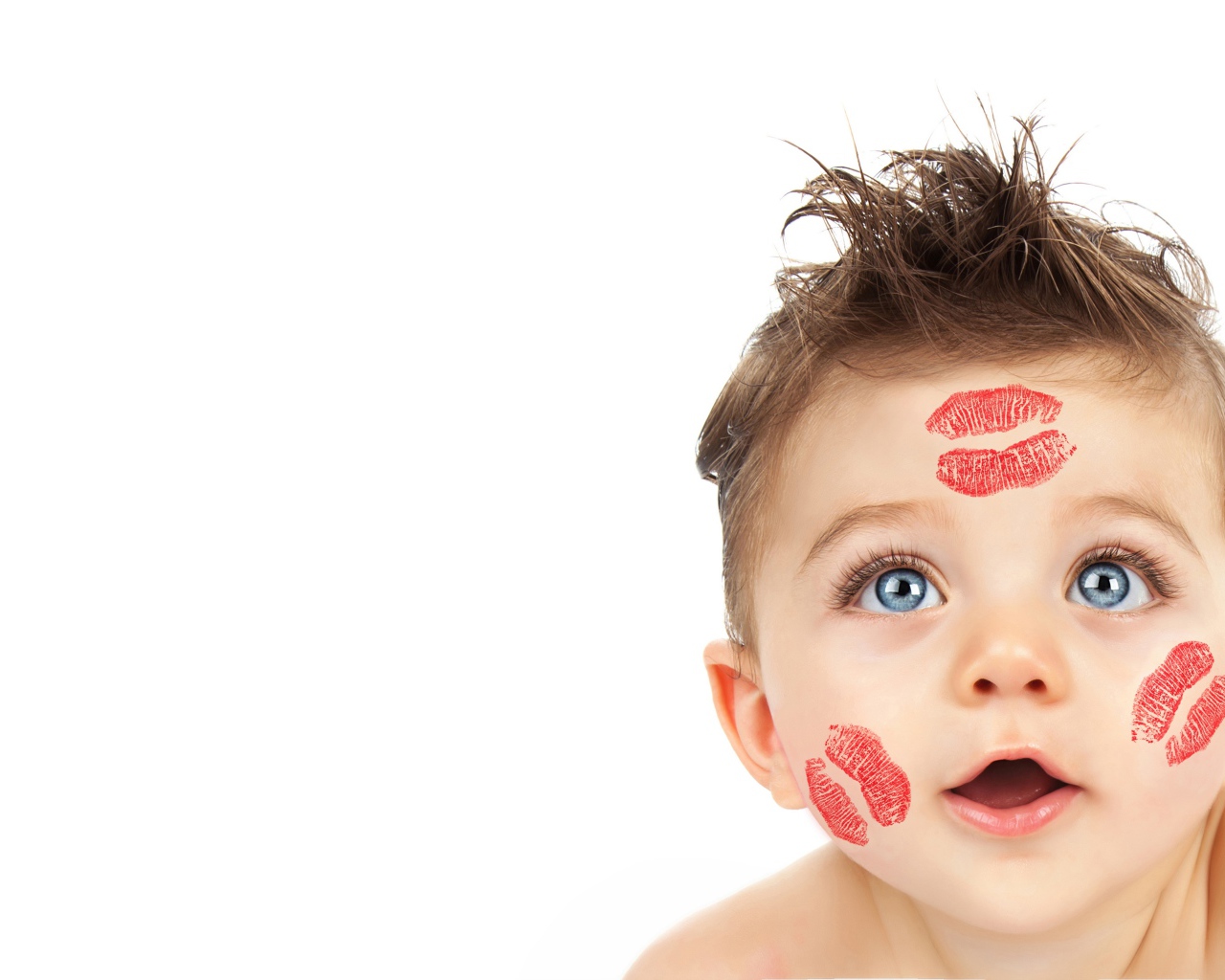 Маленький мальчик со следами от поцелуев на лице на белом фоне