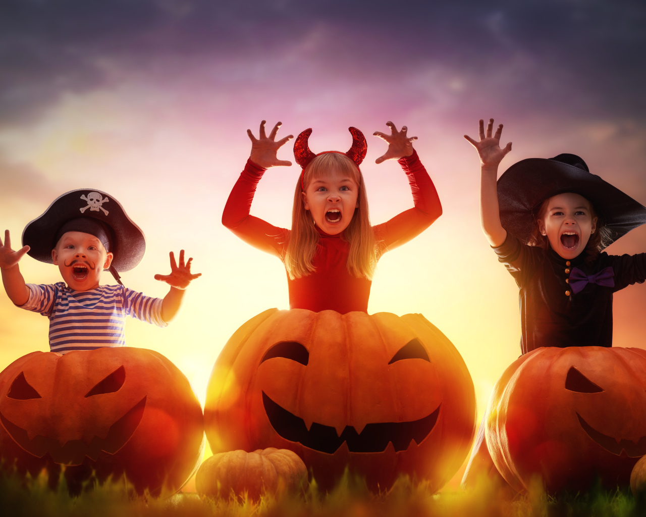 Маленькие дети в костюмах на Хэллоуин с большими тыквами