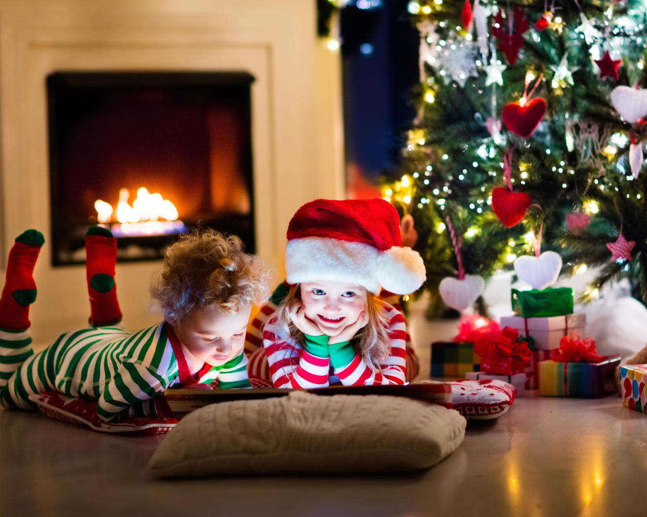 Маленькие дети в новогодних костюмах под елкой