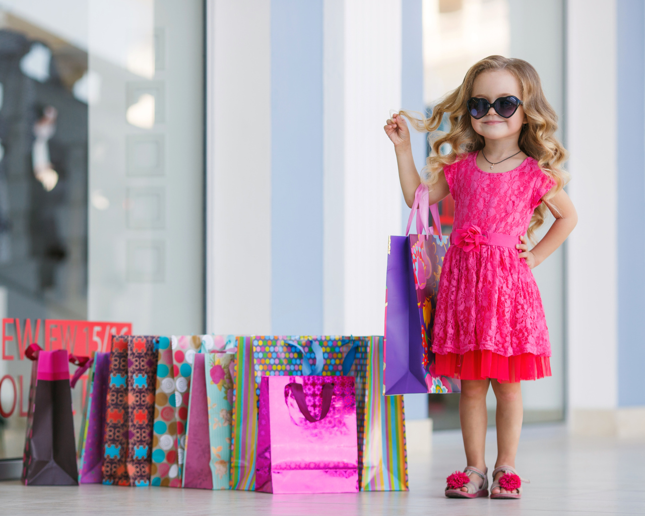 Маленькая модная девочка в красном платье с покупками