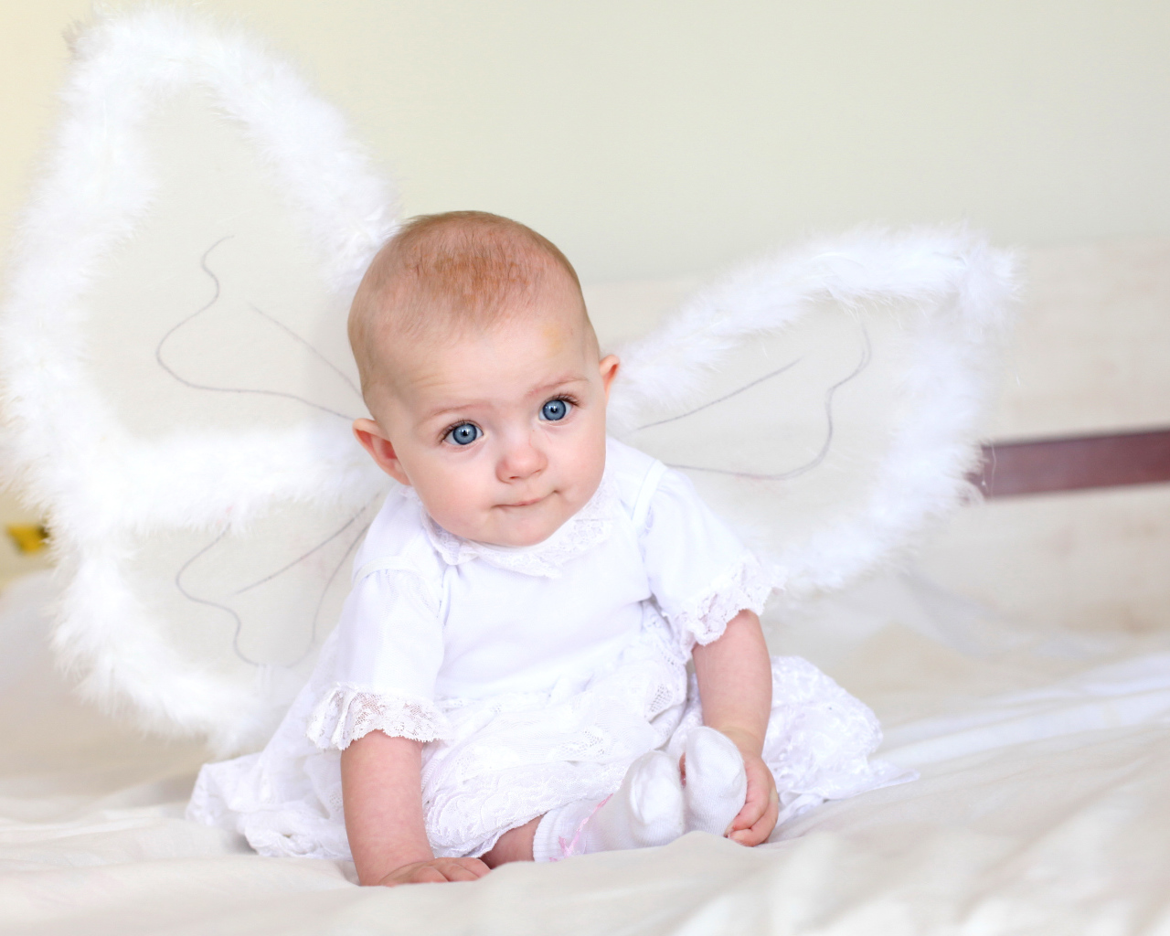 Маленькая девочка в красивом белом платье с крыльями