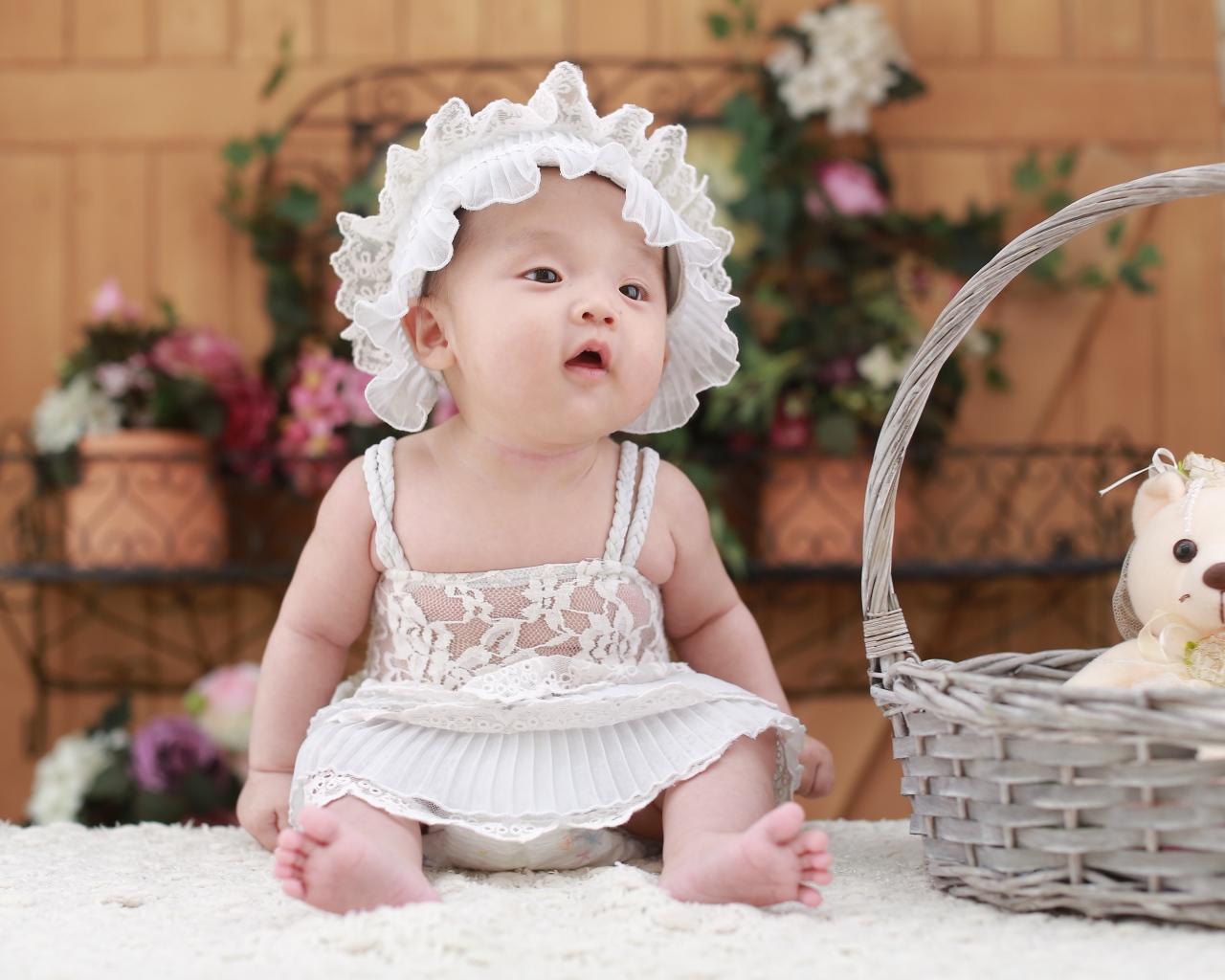 Маленькая девочка в белом платье с медвежонком в корзине