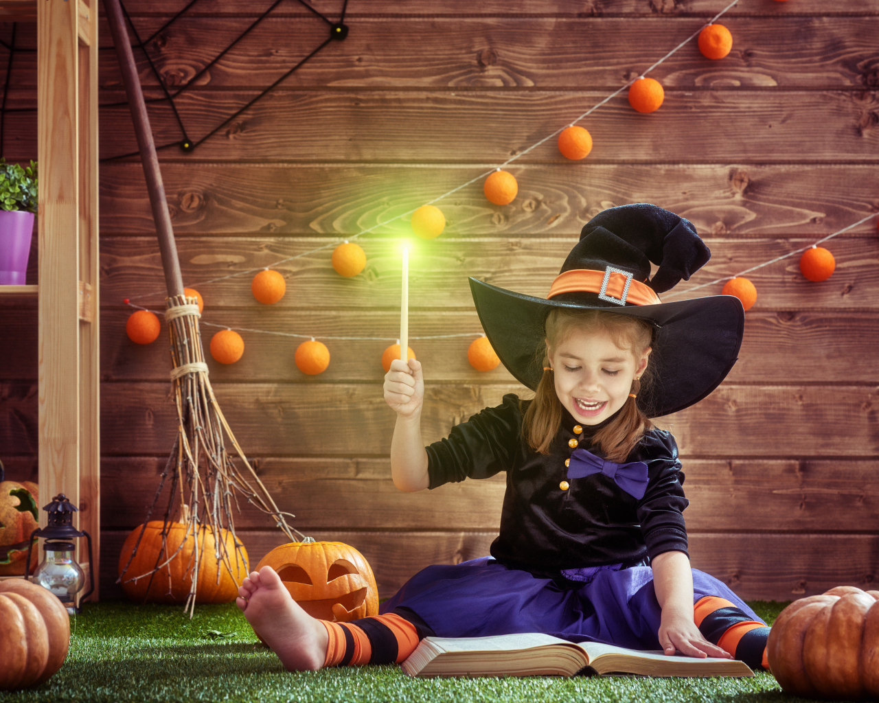 Маленькая девочка в костюме ведьмы с волшебной книгой на Хэллоуин