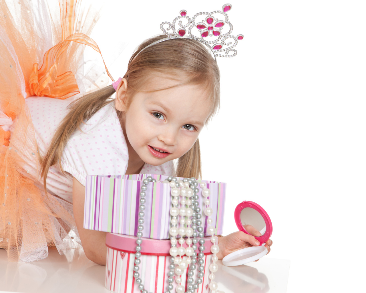 Маленькая девочка в короне на голове и с зеркалом на белом фоне