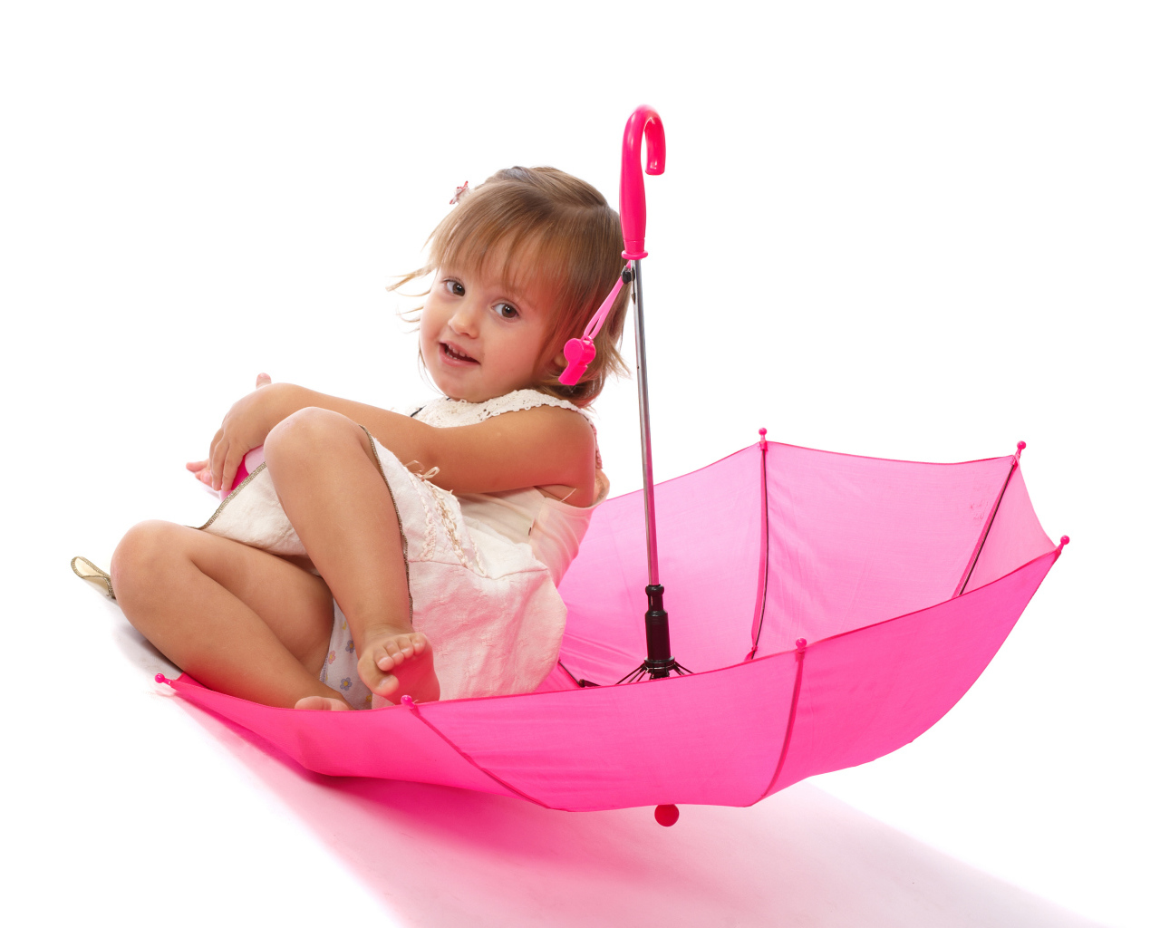 Маленькая девочка сидит в розовом зонте на белом фоне