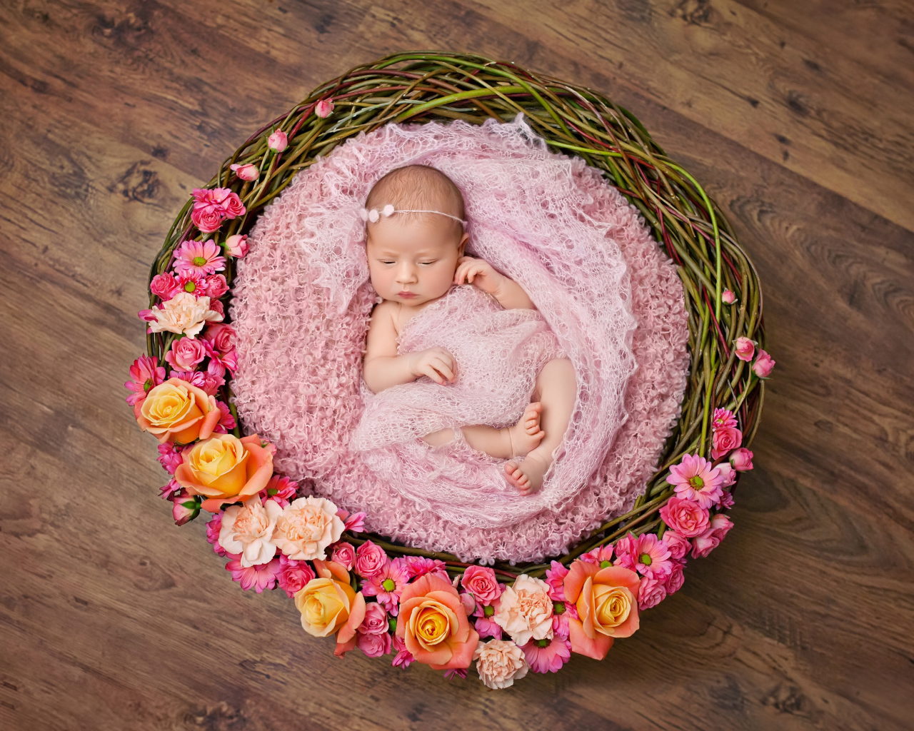 Маленькая девочка спит в корзине украшенной цветами