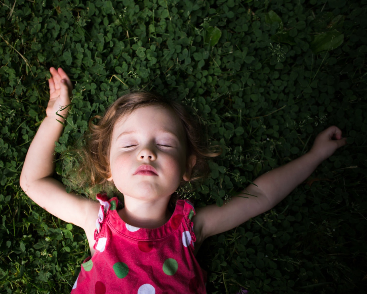 Маленькая девочка спит на зеленой траве 