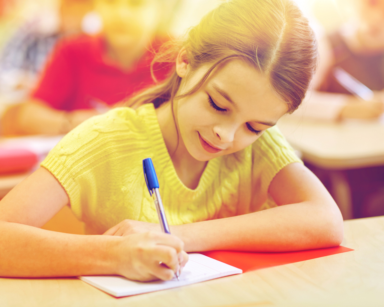 Маленькая девочка школьница пишет ручкой в тетради