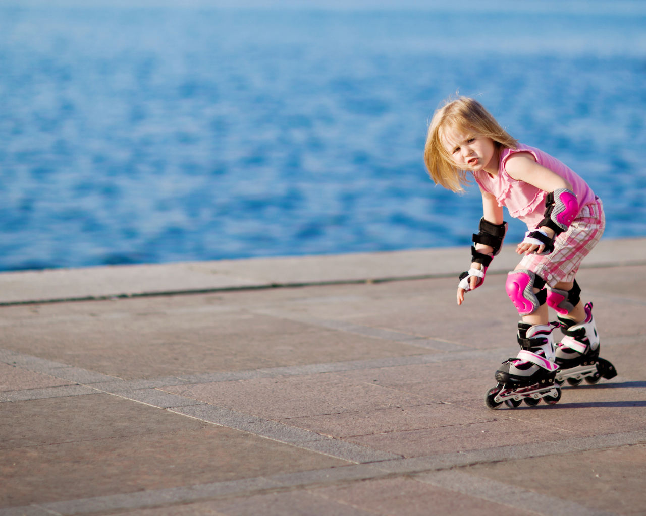 Маленькая девочка катается на роликах на побережье