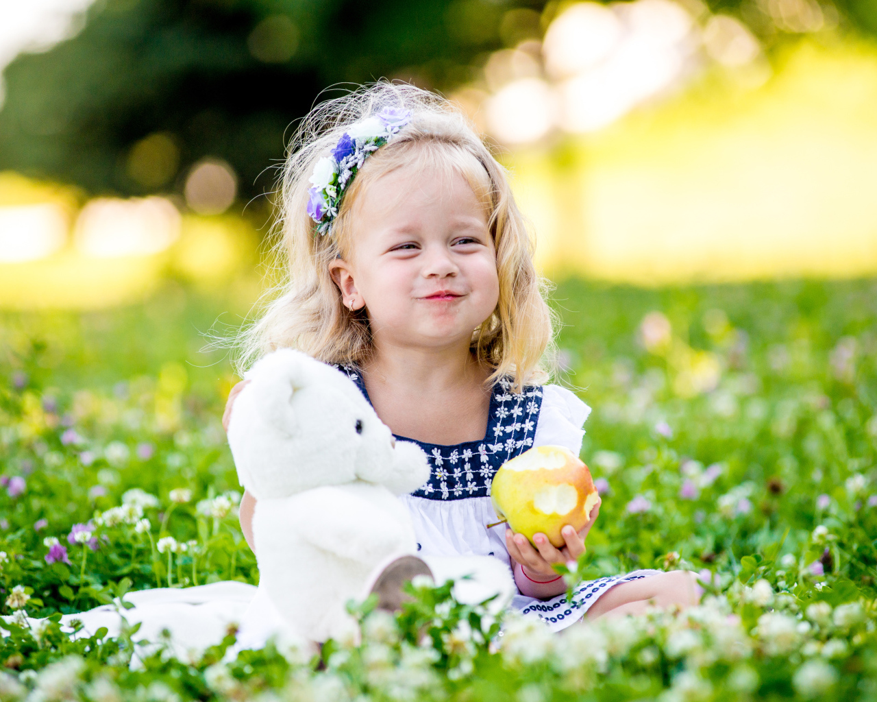 Маленькая девочка с белым медвежонком в руках и большим яблоком