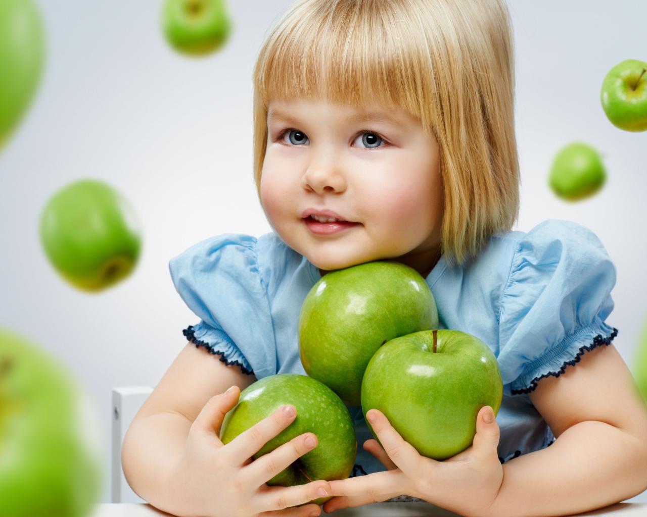 Маленькая девочка с зелеными яблоками в руках