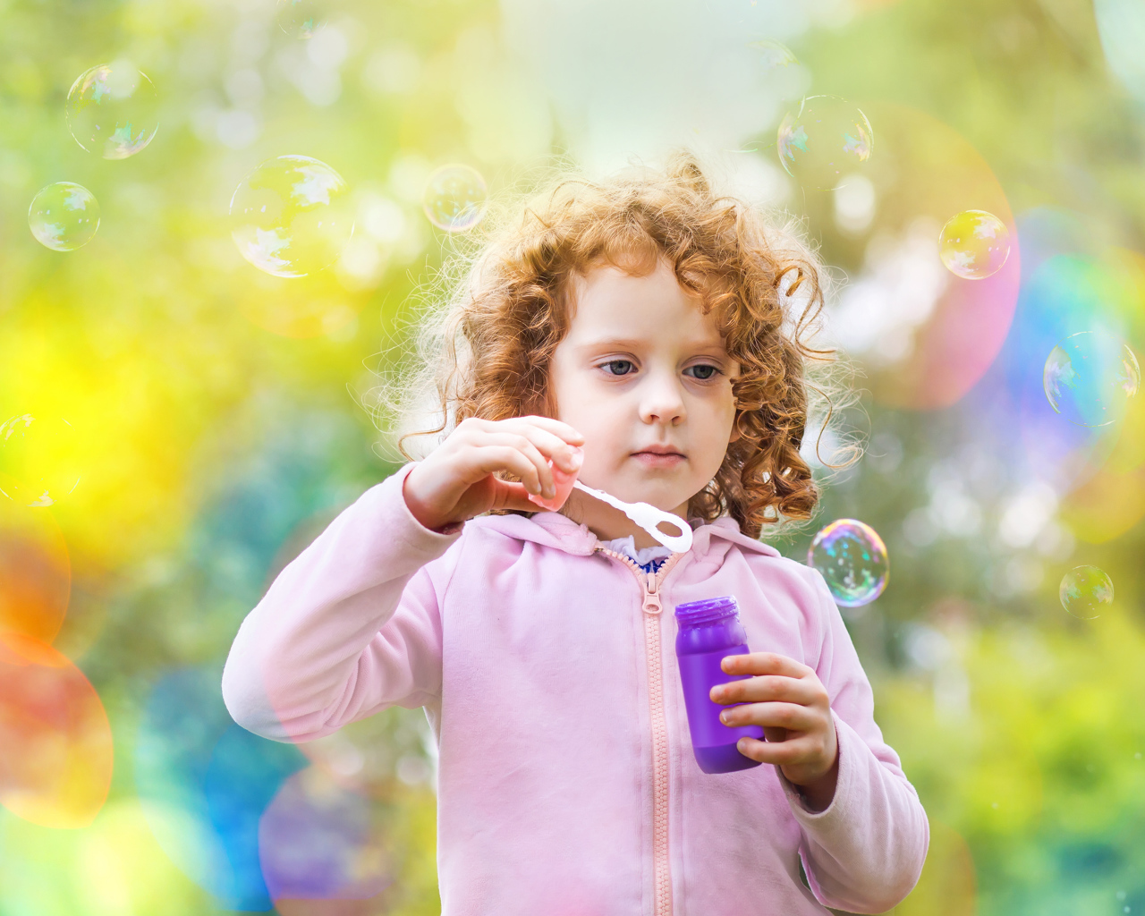 Маленькая рыжеволосая кудрявая девочка с мыльными пузырями