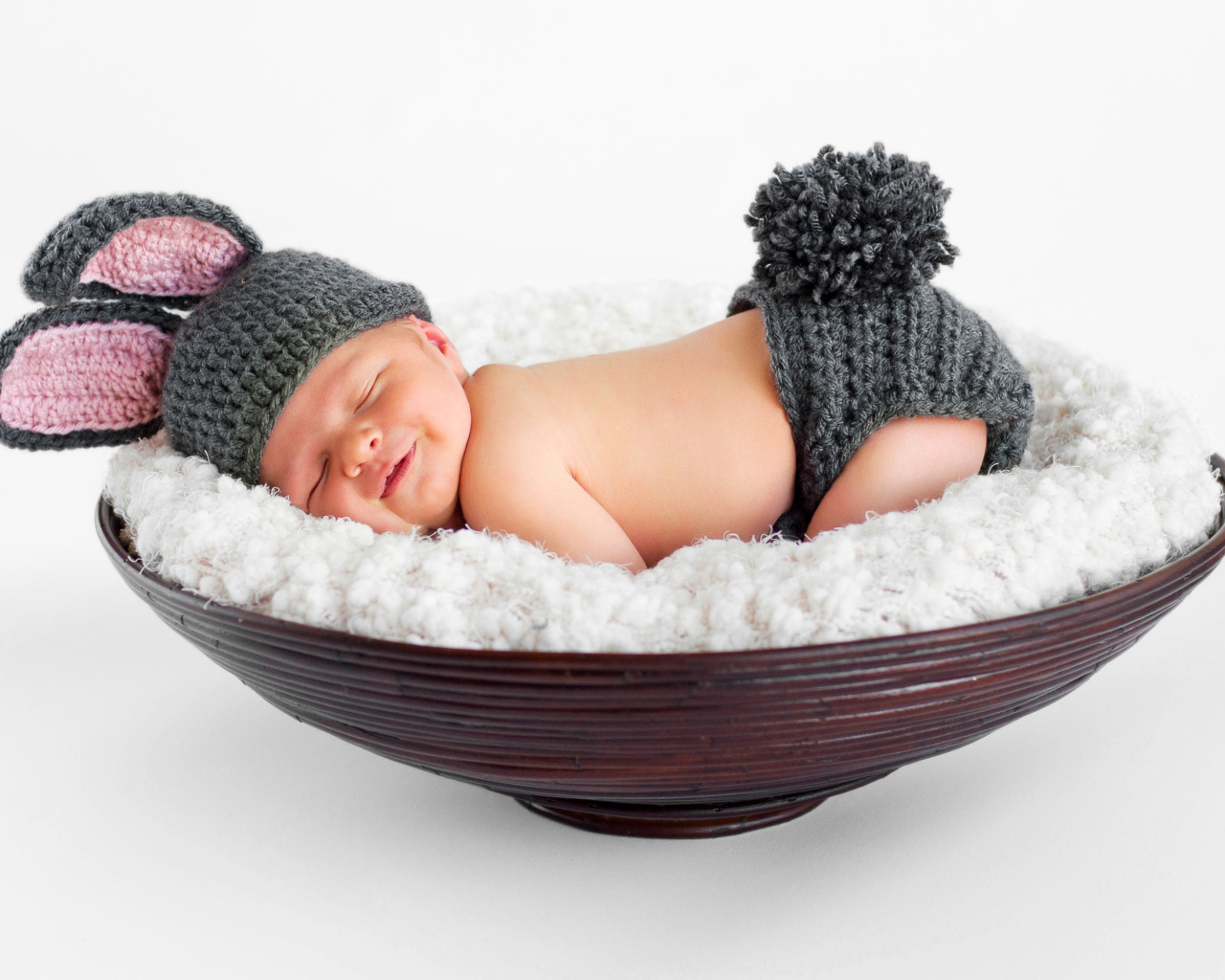 Маленький спящий грудной ребенок в вязаном костюме зайчика