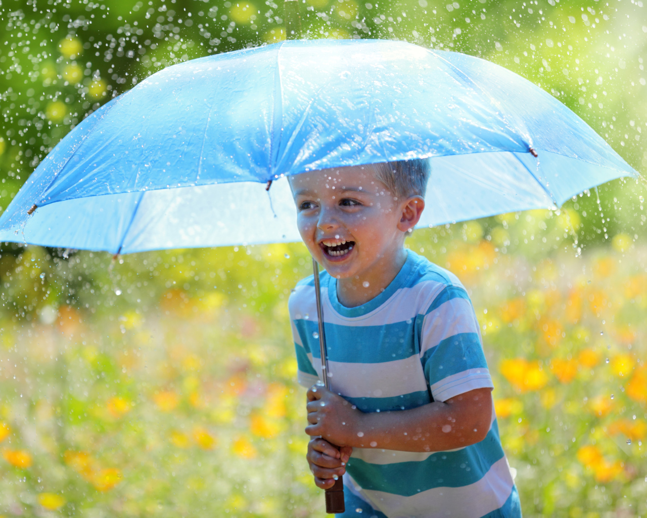 Маленький улыбающийся мальчик с голубым зонтом под дождем