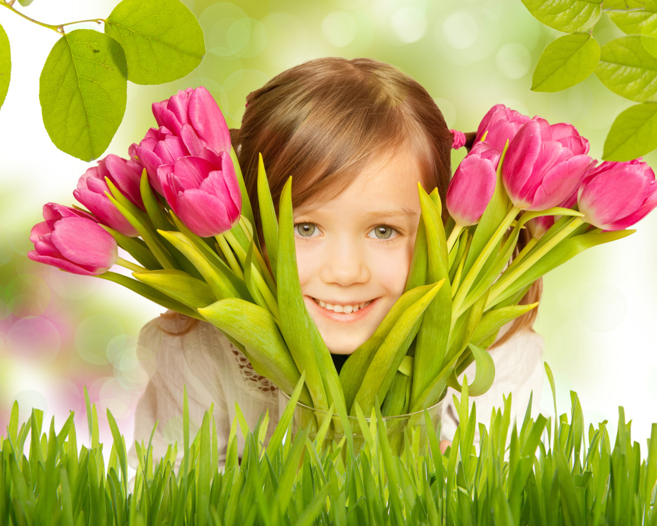 Маленькая улыбающаяся девочка шатенка с букетом розовых тюльпанов