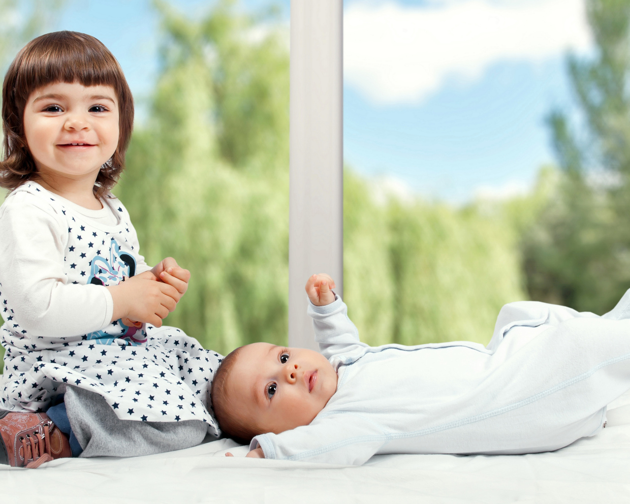 Маленькая улыбающаяся девочка с грудным ребенком