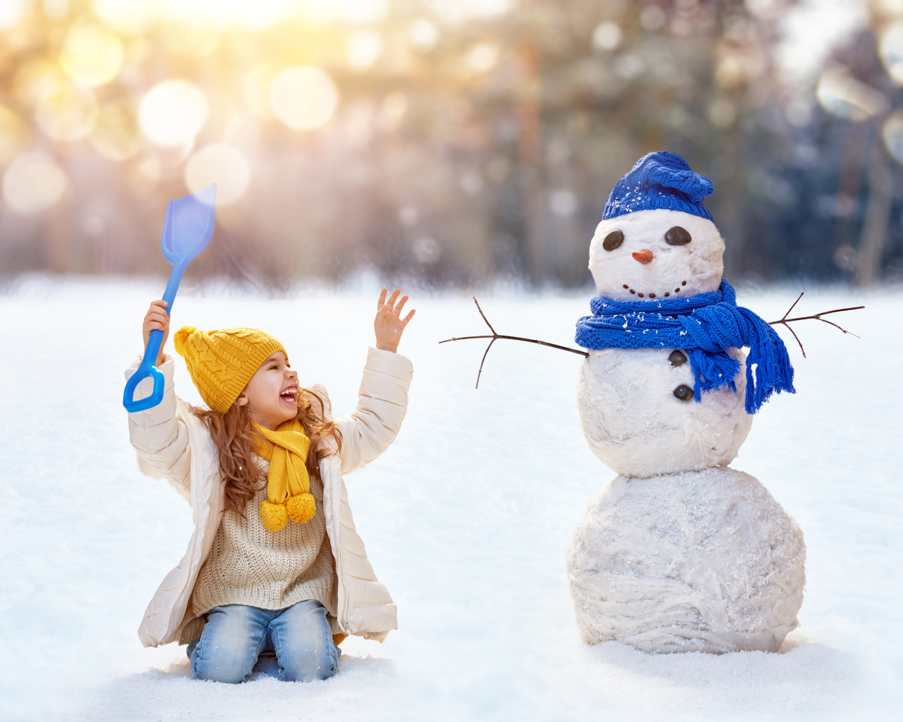 Маленькая улыбающаяся девочка со снеговиком зимой