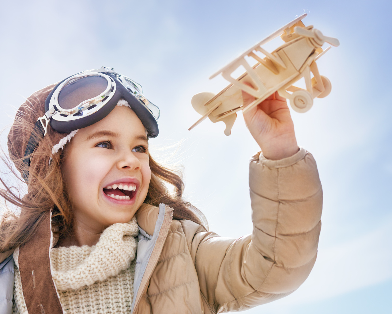 Маленькая улыбающаяся девочка с самолетом в руках 