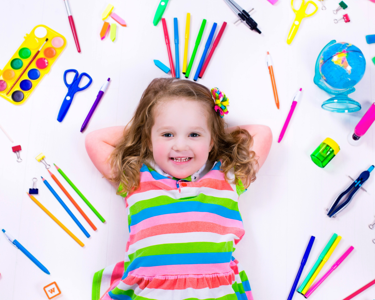 Маленькая улыбающаяся девочка со школьными принадлежностями