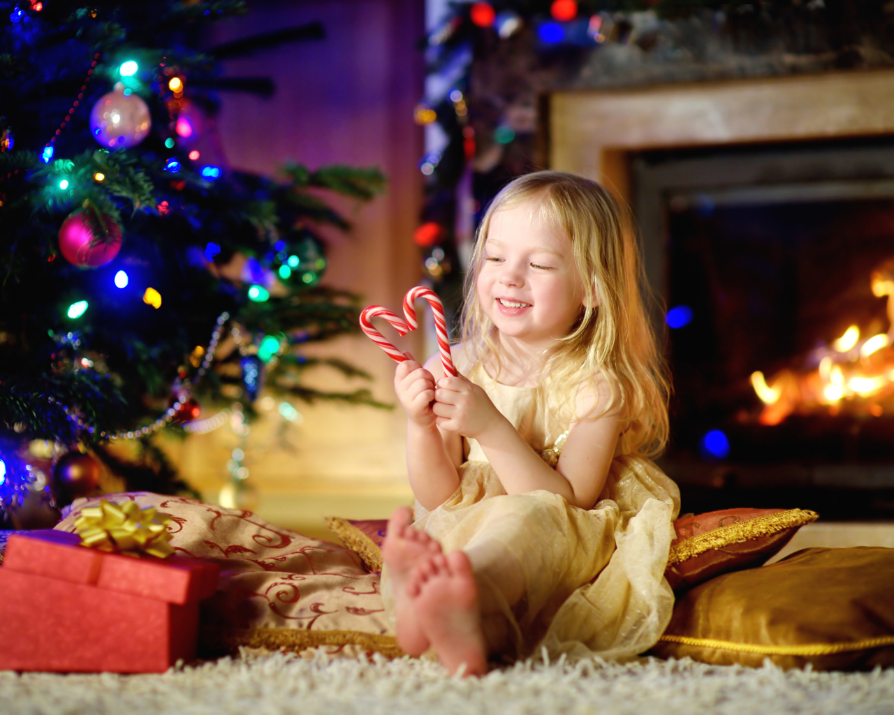 Длинноволосая девочка блондинка с леденцами у новогодней елки