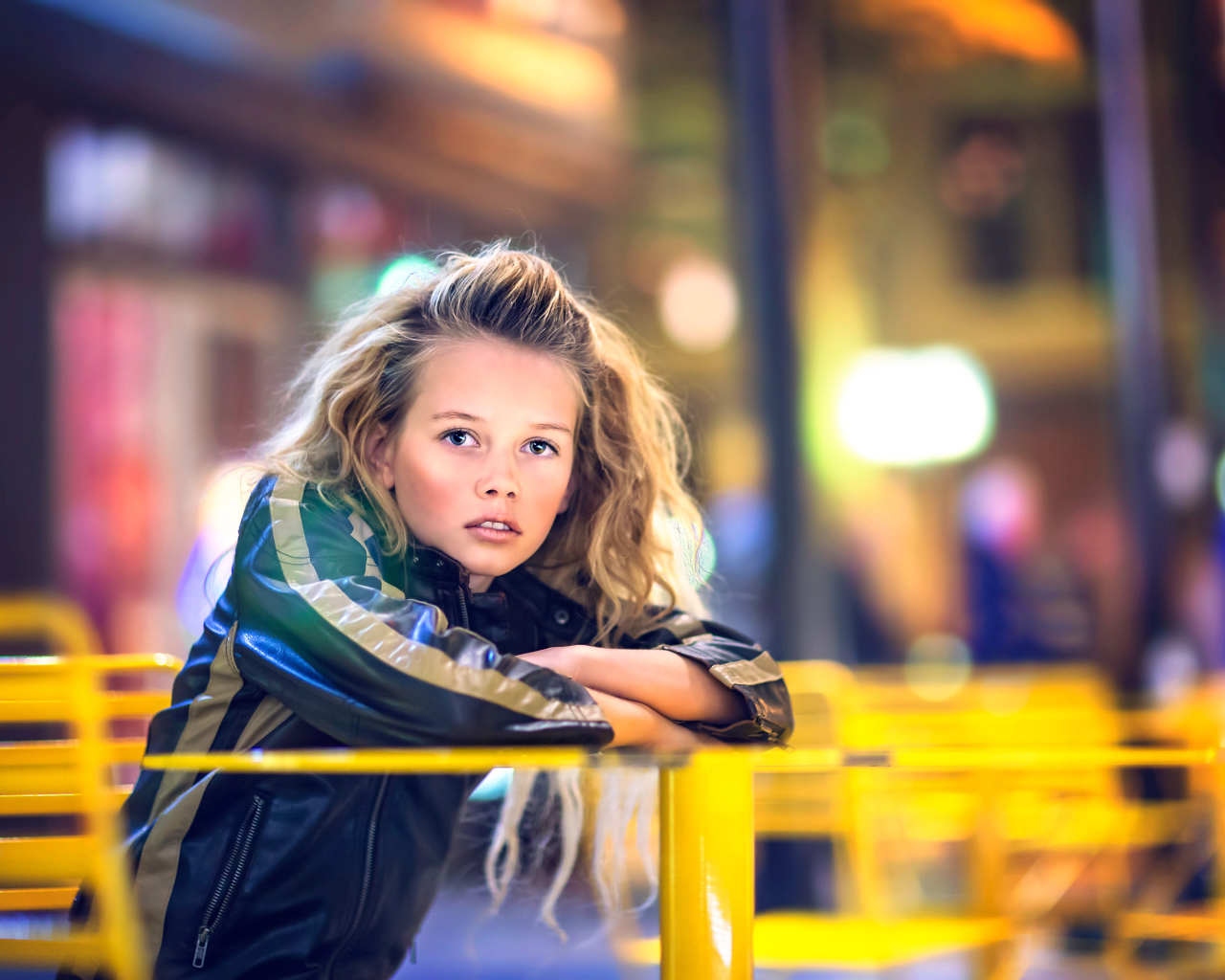 Длинноволосая девочка сидит на карусели