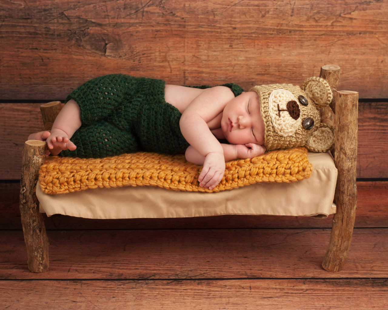 Новорожденный ребенок в костюме медвежонка спит на крошечной кровати