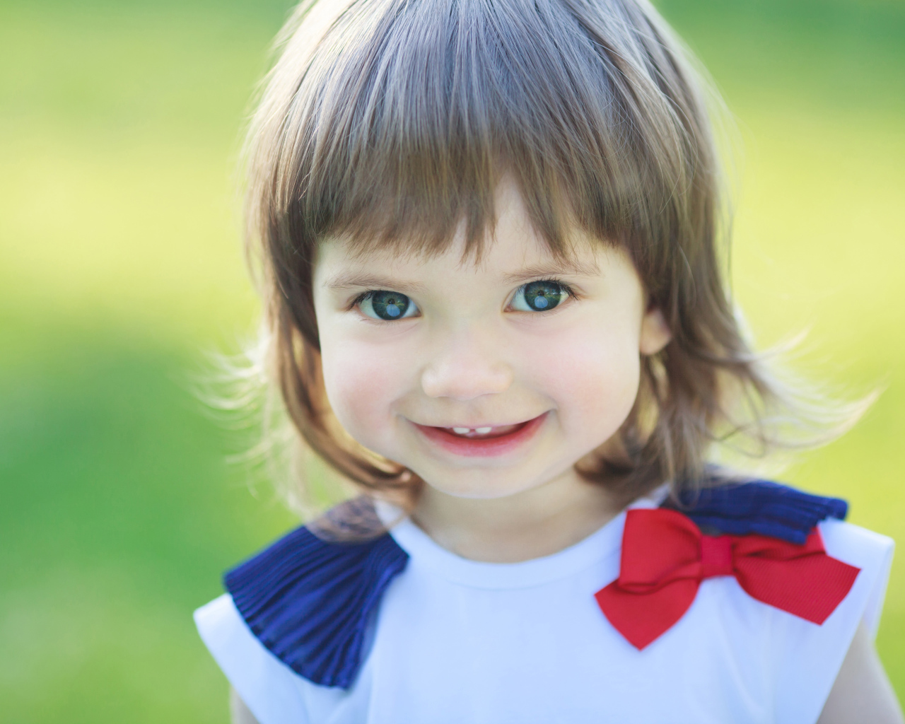 Милая улыбающаяся зеленоглазая маленькая девочка