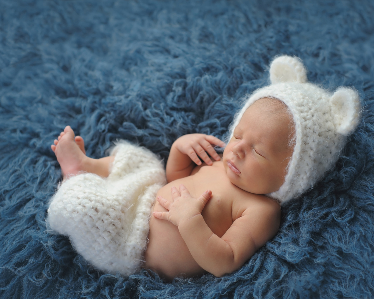 Спящий грудной ребенок в белом костюме медвежонка