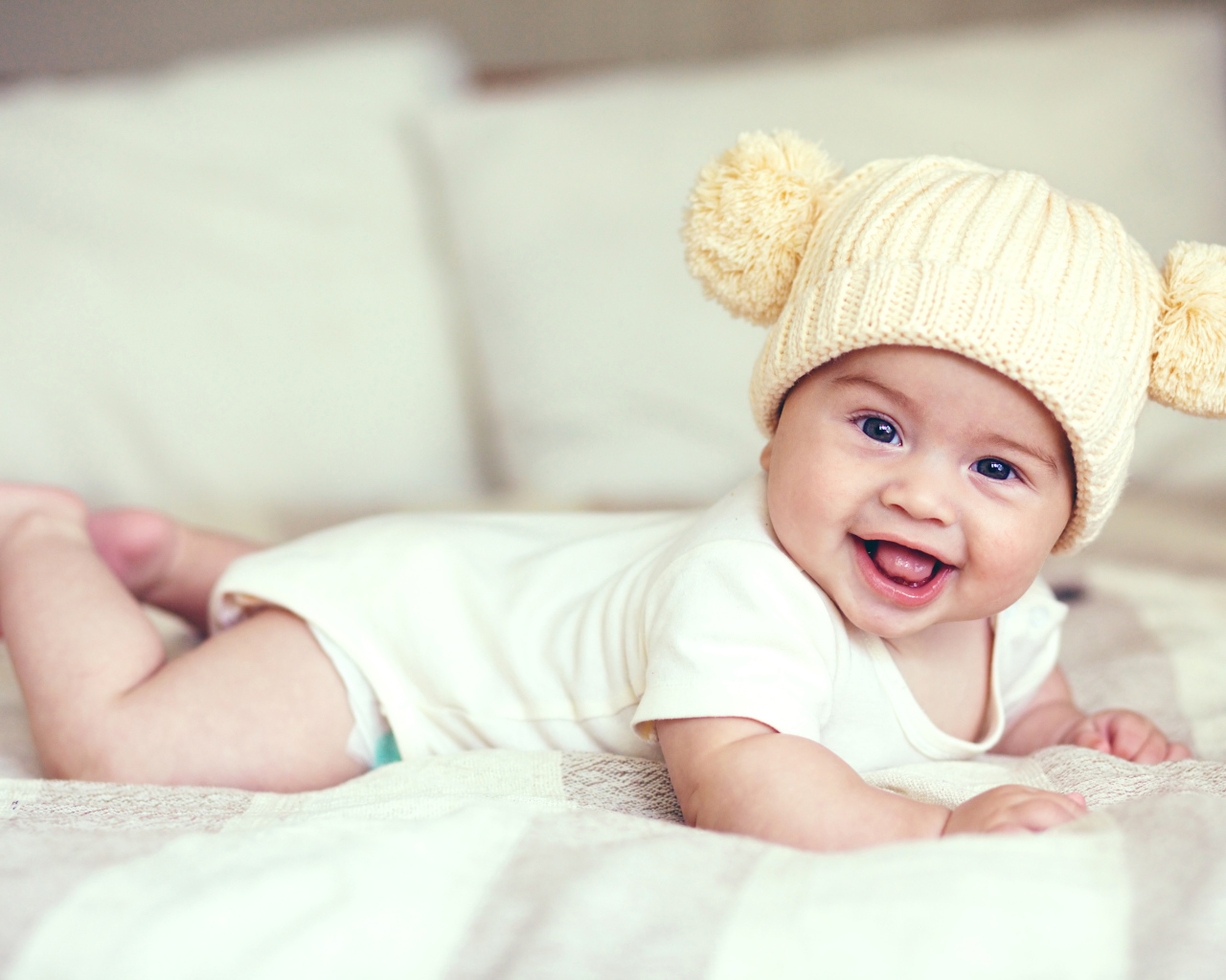 Улыбающийся грудной ребенок в забавной вязаной шапке
