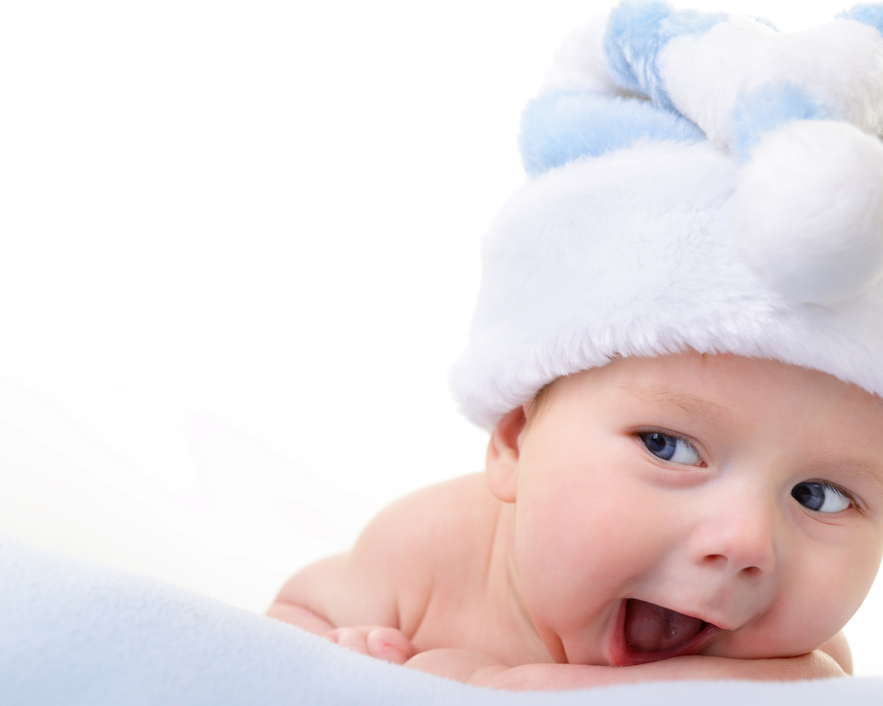 Улыбающийся грудной ребенок в голубой новогодней шапке