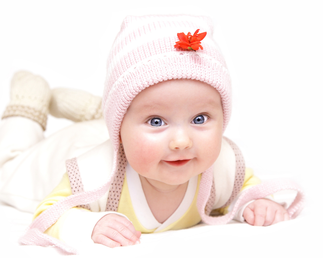 Улыбающийся голубоглазый малыш в розовой шапке