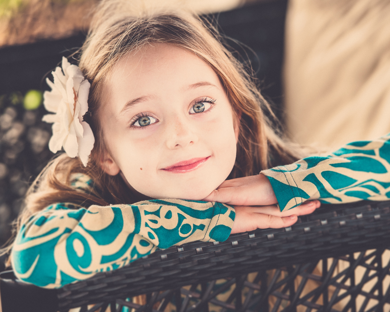 Улыбающаяся зеленоглазая девочка с белым цветком в волосах