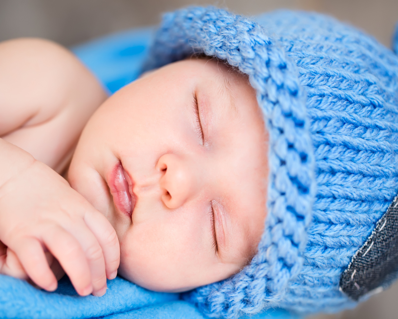 Милый спящий младенец с синей вязаной шапке