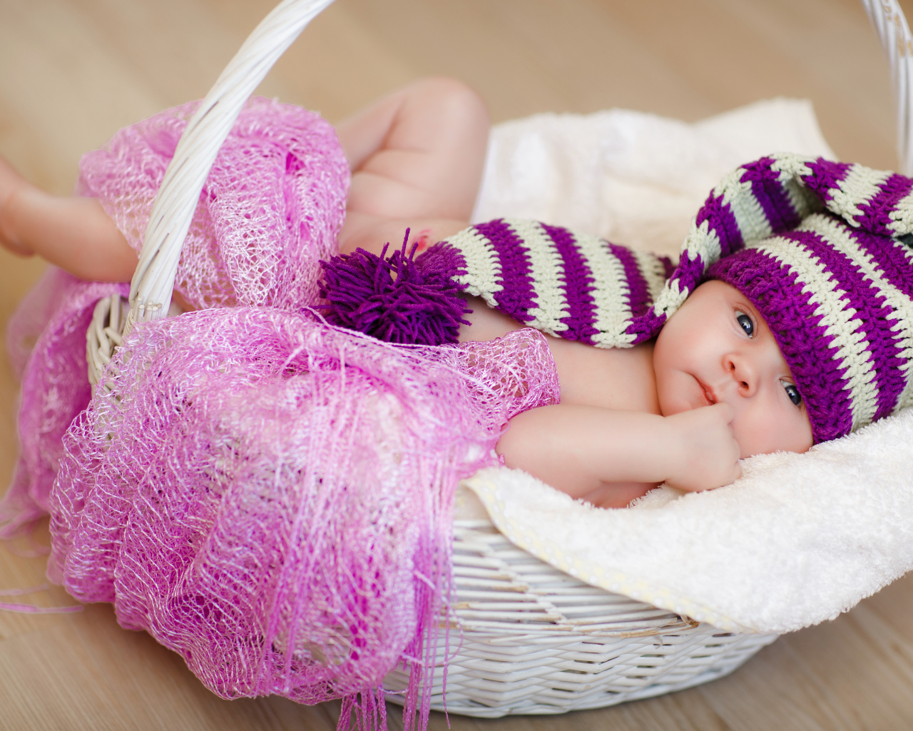Младенец в красивой вязаной шапке лежит в корзине