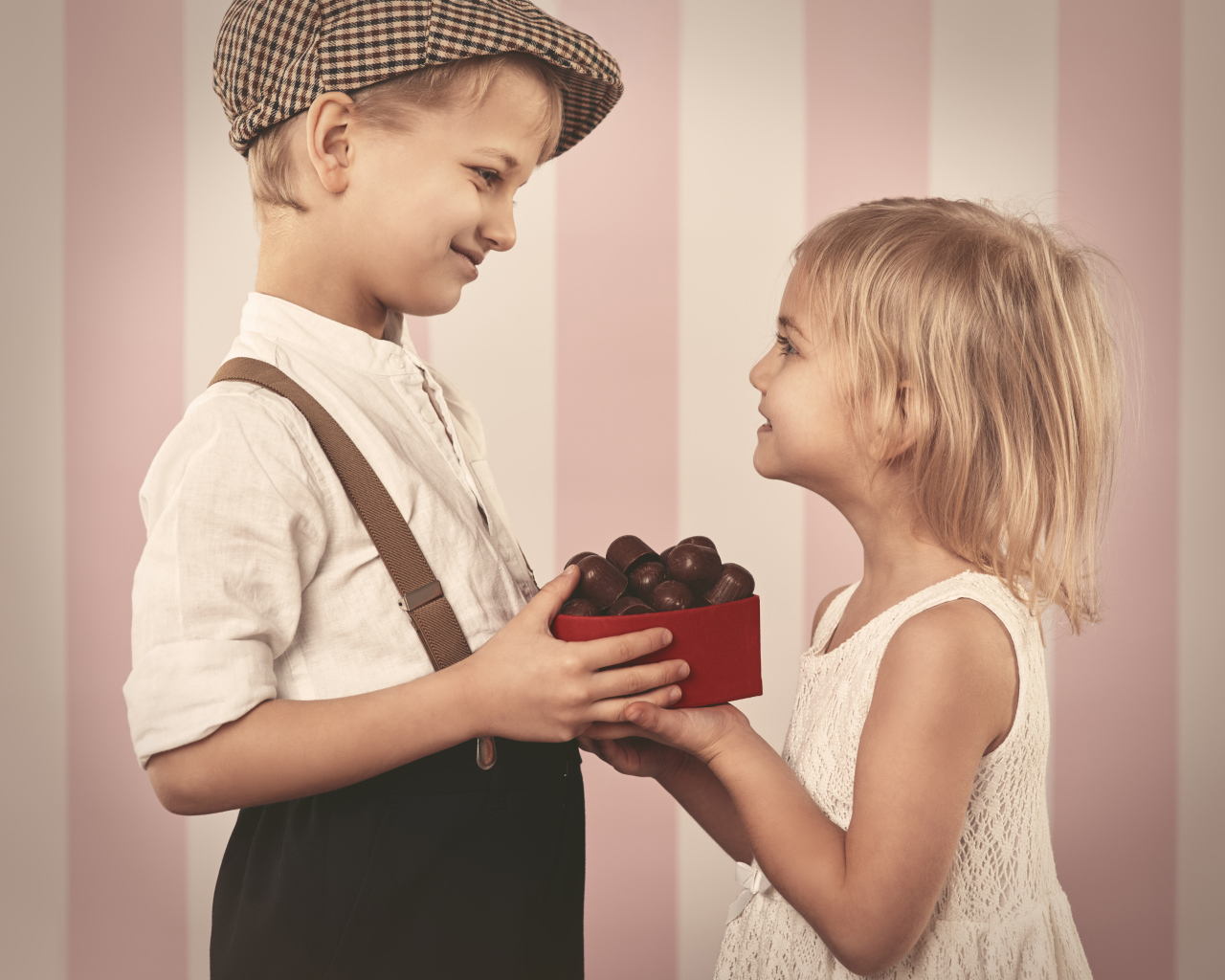 Мальчик дарит девочке коробку шоколадных конфет