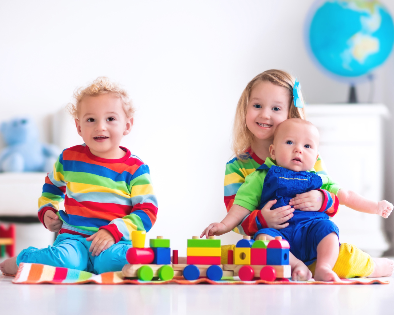 Три ребенка играют с игрушечным поездом