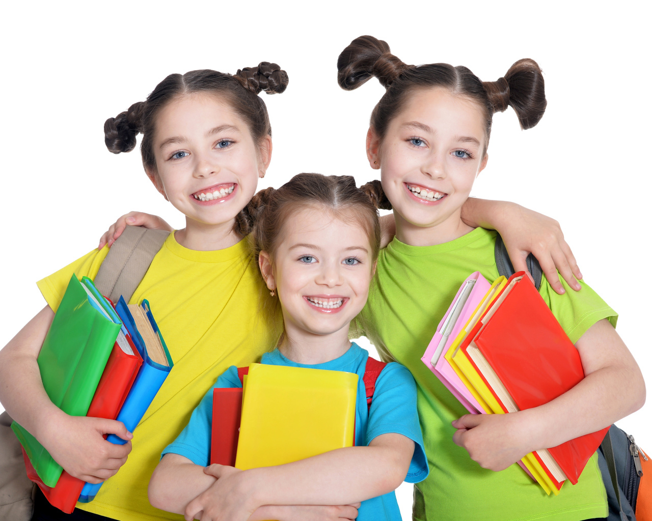 Три маленькие улыбающиеся девочки с книгами на белом фоне