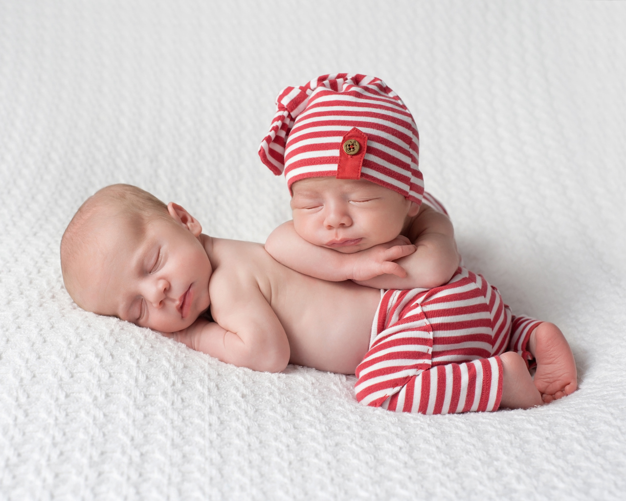 Два милых спящих младенца в полосатых костюмах
