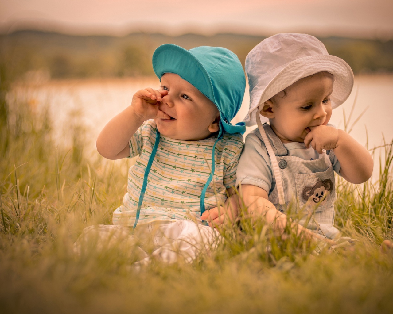 Два милых малыша в зеленой траве летом 